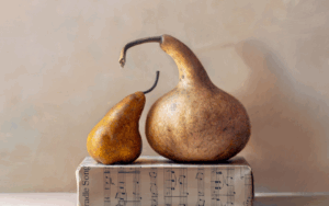 Two gourds, one small and one large, rest on a closed book with visible sheet music against a neutral background.