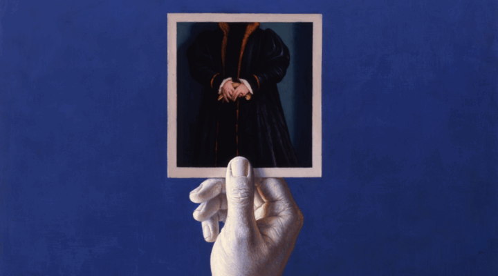 A hand holds a photo featuring a person in a dark coat with their head cropped out, against a solid blue background.