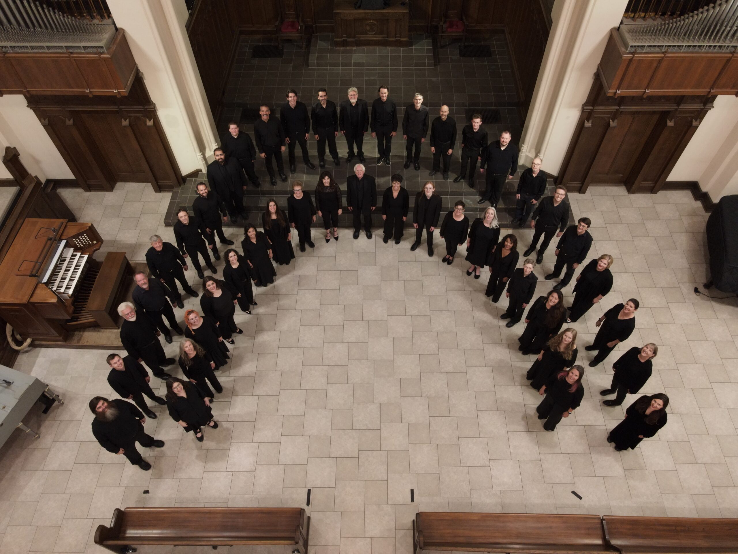 Overhead drone view of the Ars Nova Singers standing in a wide arc in a church chancel